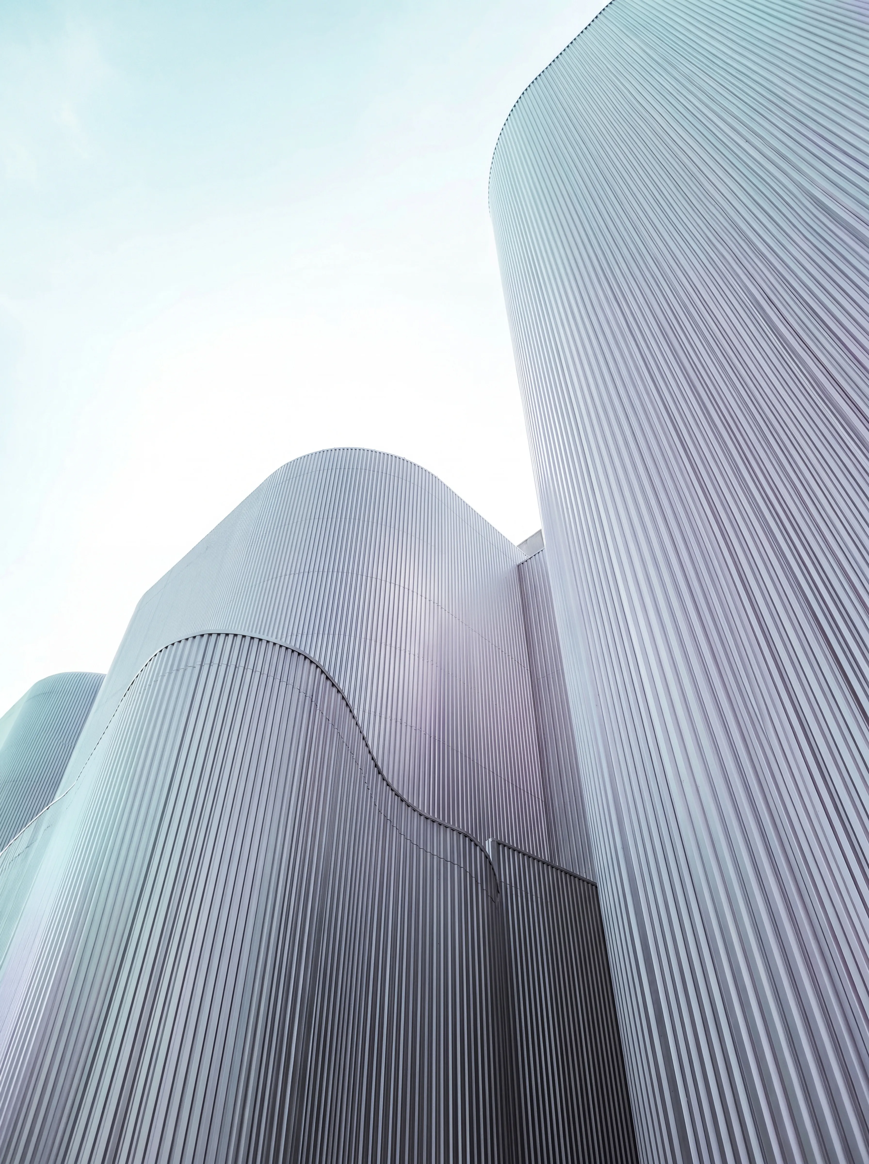 Curved metallic architectural structures against an open sky